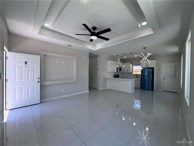 Unfurnished living room with a tray ceiling, a ceiling fan, light tile patterned floors, and recessed lighting
