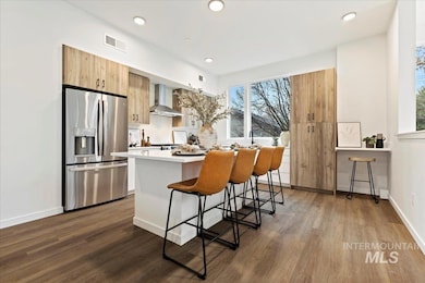 Kitchen with stainless steel fridge, wall chimney exhaust hood, dark wood-type flooring, a center island, and recessed lighting