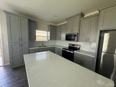 Kitchen featuring appliances with stainless steel finishes, gray cabinets, a sink, and tasteful backsplash