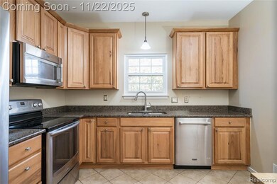 Kitchen featuring stainless steel appliances, dark stone counters, hanging light fixtures, and light tile patterned floors