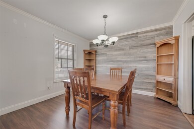 Dining area featuring ornamental molding, dark wood-type flooring, a chandelier, an accent wall, and wooden walls