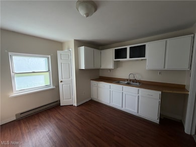 Kitchen featuring white cabinetry, baseboard heating, and dark wood-style floors