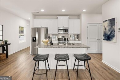 Kitchen featuring range, stainless steel microwave, a sink, white cabinetry, and decorative backsplash