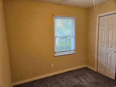 Unfurnished bedroom with dark carpet, a closet, and a textured ceiling