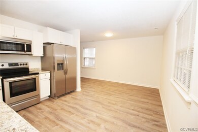 Kitchen with light hardwood / wood-style flooring, light stone countertops, white cabinets, and stainless steel appliances