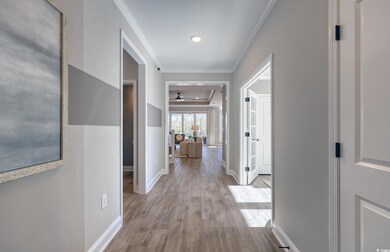 Hall with light wood-style flooring, baseboards, and ornamental molding