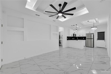 Unfurnished living room with a tray ceiling and ceiling fan with notable chandelier