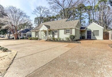 View of front facade featuring driveway, roof with shingles, covered porch, and brick siding