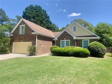 View of front of home with driveway, brick siding, a garage, and a front yard