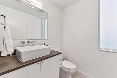 Bathroom with vanity, toilet, and baseboards