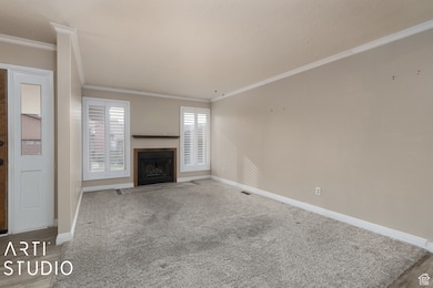 Unfurnished living room with a fireplace with flush hearth, ornamental molding, and carpet flooring