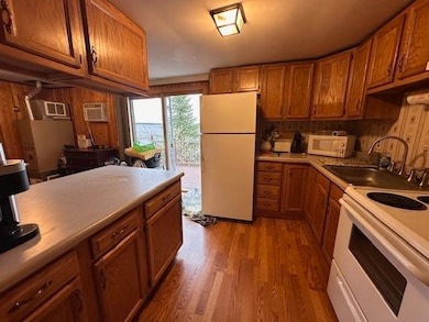 Kitchen featuring white appliances, a sink, light wood-style flooring, and brown cabinets