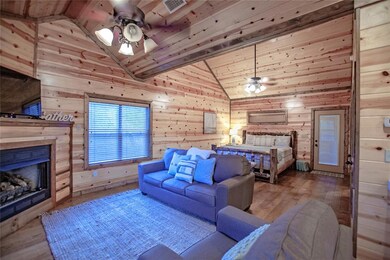 Bedroom with wood walls, wood finished floors, a fireplace, wood ceiling, and high vaulted ceiling