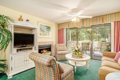 Soft Carpeted living room with ceiling fan, a tiled fireplace, and lush private access and view of the grounds.