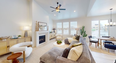 Living area featuring high vaulted ceiling, light wood-type flooring, a chandelier, a glass covered fireplace, and recessed lighting