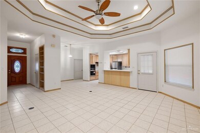 Unfurnished living room featuring crown molding, light tile patterned flooring, a raised ceiling, and ceiling fan
