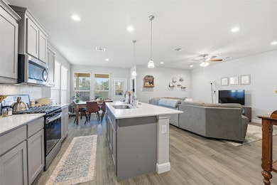 Kitchen with gray cabinets, stainless steel appliances, recessed lighting, hanging light fixtures, and open floor plan
