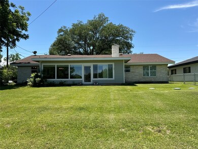 Back of house with a chimney, stone siding, and a