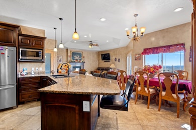 Kitchen featuring light stone counters, a ceiling fan, dark brown cabinets, a raised ceiling, and stainless steel appliances