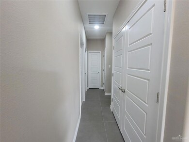 Corridor featuring dark tile patterned floors, baseboards, visible vents, and attic access