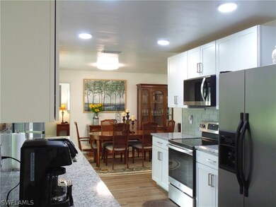 Kitchen featuring light hardwood / wood-style floors, stainless steel appliances, white cabinets, light stone counters, and backsplash