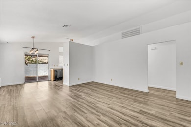 Unfurnished living room with light wood-style floors and vaulted ceiling