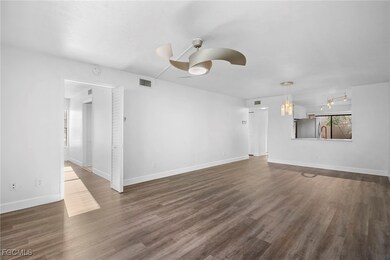 Unfurnished living room featuring ceiling fan and dark wood-style floors