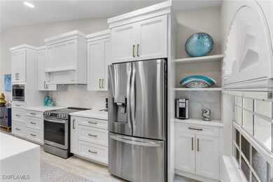 Kitchen featuring open shelves, stainless steel appliances, tasteful backsplash, white cabinets, and vaulted ceiling