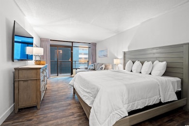 Bedroom featuring a textured ceiling, access to exterior, dark wood-style floors, and baseboards
