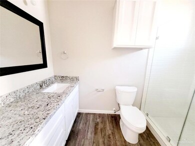 Bathroom with a shower stall, toilet, wood finished floors, and vanity