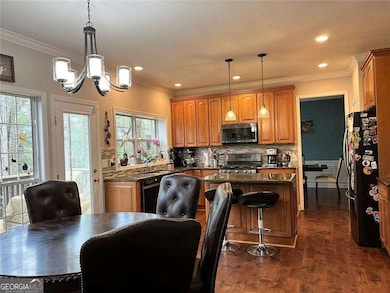 Kitchen featuring black appliances, a kitchen island, a chandelier, brown cabinetry, and recessed lighting