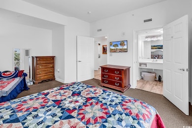 Bedroom with carpet floors, ensuite bathroom, and baseboards