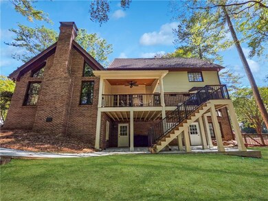 Back of property featuring a ceiling fan, a patio area, a lawn, and brick siding