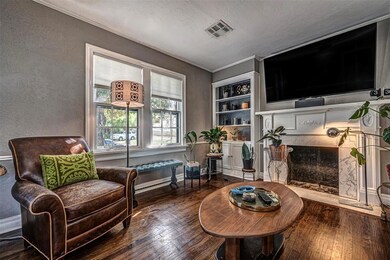 The living room has warm brown stained floors that take the eye to the mock fireplace with it's decorative mantel and  grey veined white stone surround.