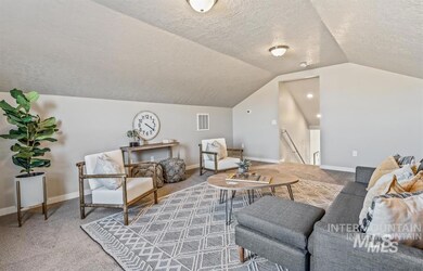 Carpeted living area with a textured ceiling and vaulted ceiling