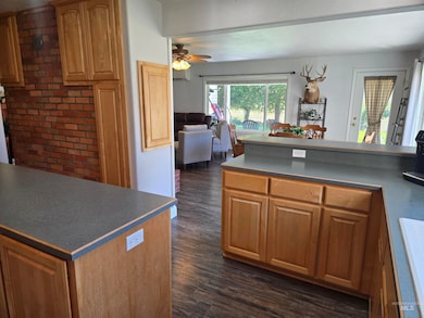 Kitchen featuring dark wood finished floors, a ceiling fan, dark countertops, and open floor plan