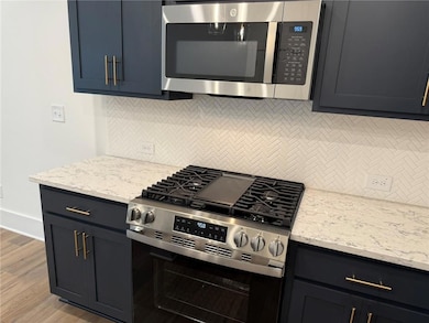 Kitchen featuring appliances with stainless steel finishes, backsplash, baseboards, and light wood finished floors
