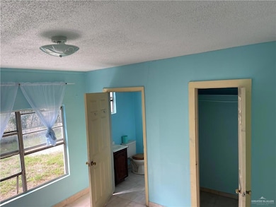 Tiled bedroom with connected bathroom and a textured ceiling
