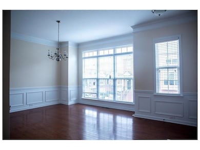 Unfurnished room with a chandelier, healthy amount of natural light, crown molding, wainscoting, and a decorative wall