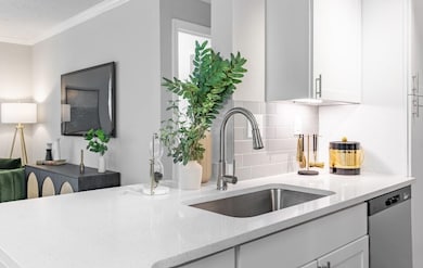 Kitchen featuring sink, white cabinetry, dishwasher, and tasteful backsplash