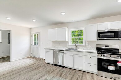 Kitchen featuring baseboards, a sink, stainless st