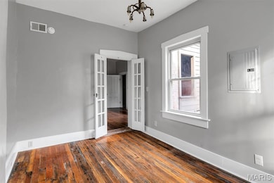 Unfurnished room featuring french doors, electric panel, and dark wood-style floors