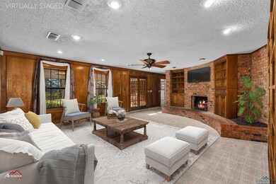 Carpeted living room with a fireplace, wood walls, a textured ceiling, and ceiling fan