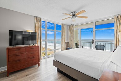 Bedroom with a textured ceiling, a water view, wood finished floors, access to exterior, and a wall of windows