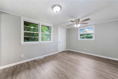 Unfurnished room with wood finished floors, a ceiling fan, a textured ceiling, and baseboards