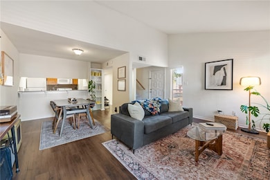 Living area with dark wood-style flooring and high vaulted ceiling