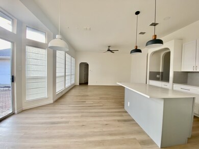Kitchen with arched walkways, decorative light fixtures, a kitchen island, and ceiling fan