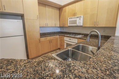 Kitchen with a sink, light brown cabinetry, dark s