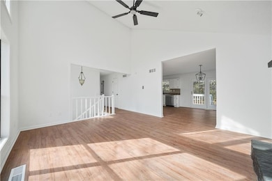 Unfurnished living room with visible vents, high vaulted ceiling, a ceiling fan, and wood finished floors