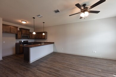 Kitchen featuring dark countertops, a peninsula, dark brown cabinetry, appliances with stainless steel finishes, and open floor plan